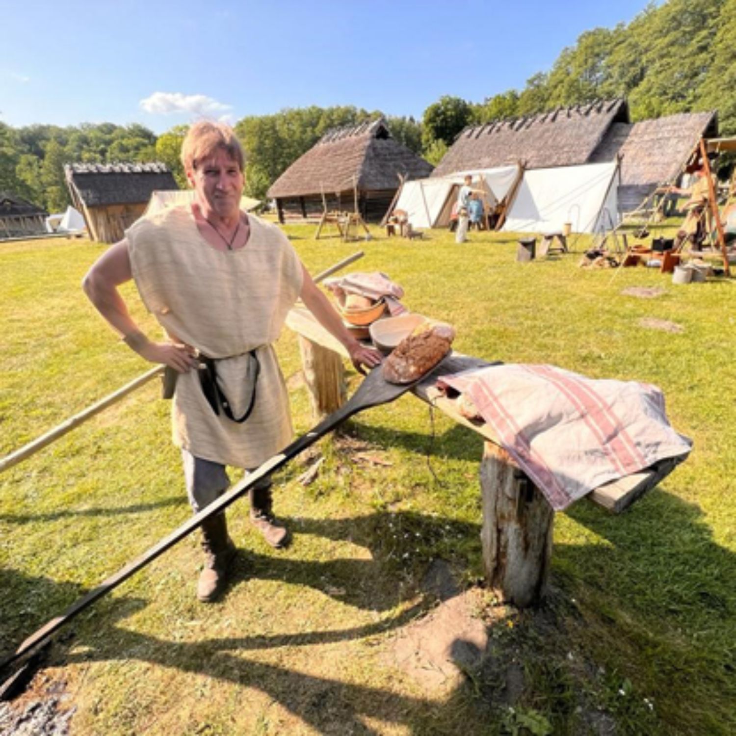 Ein mittelalterlich gekleideter Mann steht an einem Holztablett. LAKD M-V/LA