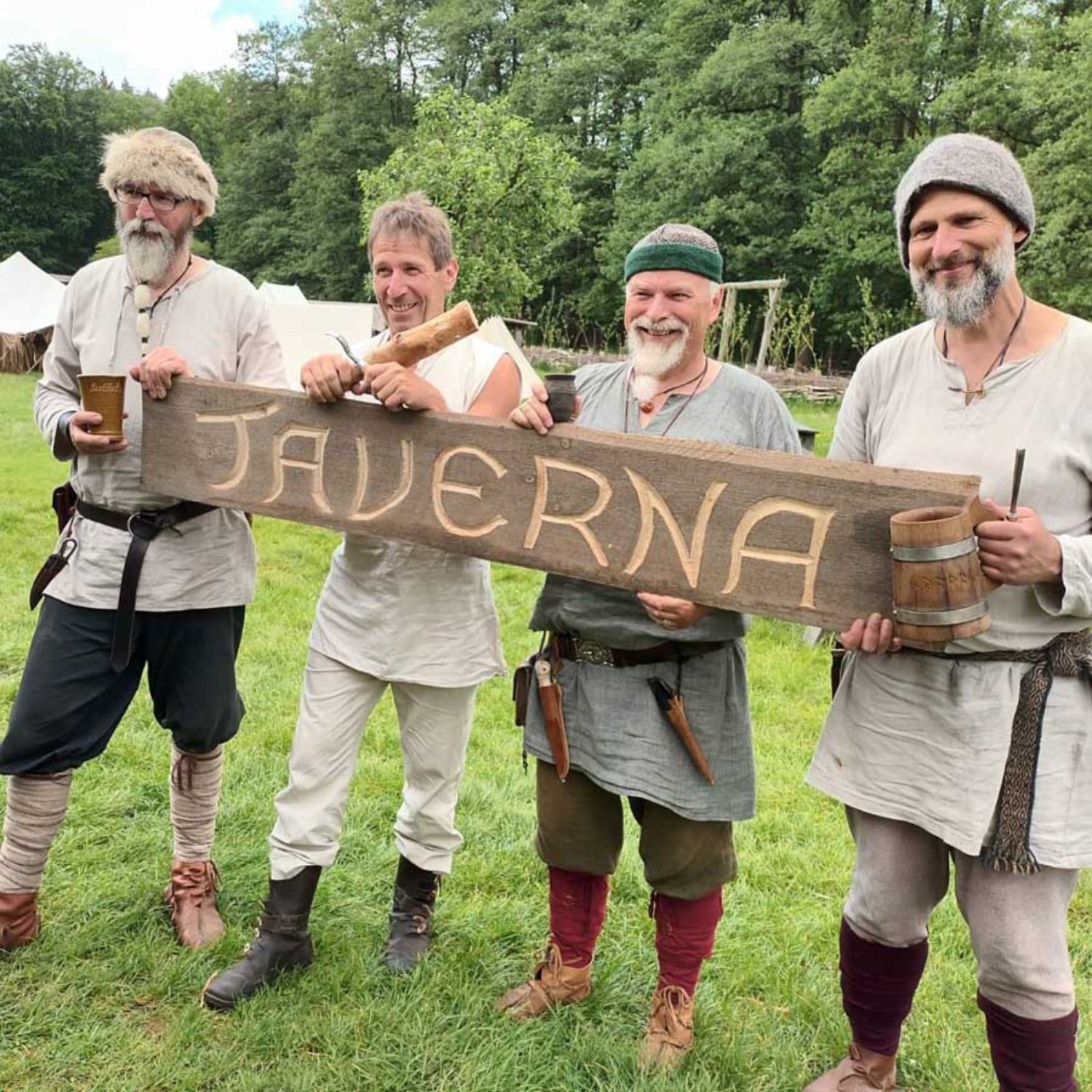 Männer in traditioneller, historischer Kleidung tragen ein Schild mit der Aufschrift Taverna. LAKD M-V/LA